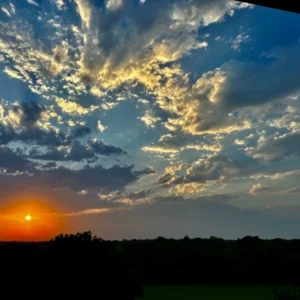 A sunset with clouds in the sky and trees.