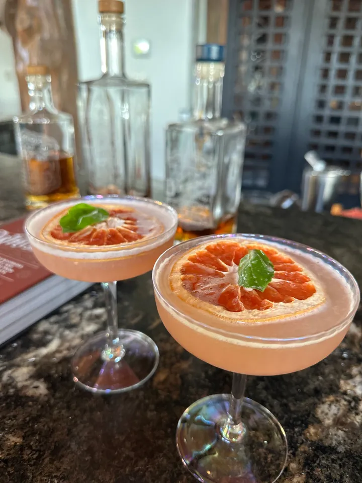 Two glasses of grapefruit cocktails on a table.