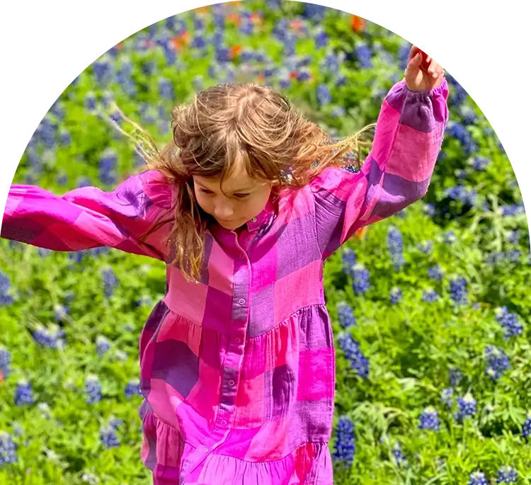 A little girl in pink pajamas standing on top of a field.